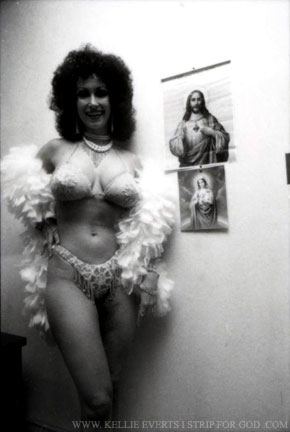 Buxom brunette in white feather boa flashes in front of the camera dressing to walk out on-stage