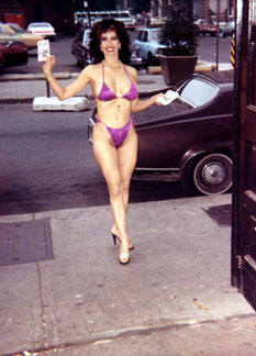 Purple bikini, buxom babe on the sreet with pubic hair showing through panty while handing out Catholic literature on street corner