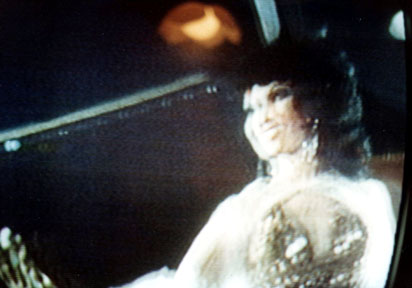 Kellie Everts, gorgeous stripper in golden sequined, fish scale cape and gown performing in Burlesque theatre