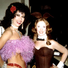 Backstage at the Playclub in 1978 Chicago. Kellie with rose in hair, pink boa covering her topless breasts, thin waiste holding up sequined ruby panties, posing with a Playboy Bunny